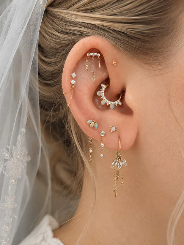 Close-up van bridal ear styling met gouden piercingsieraden en parels