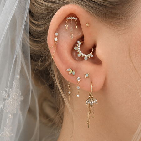 Close-up van bridal ear styling met gouden piercingsieraden en parels