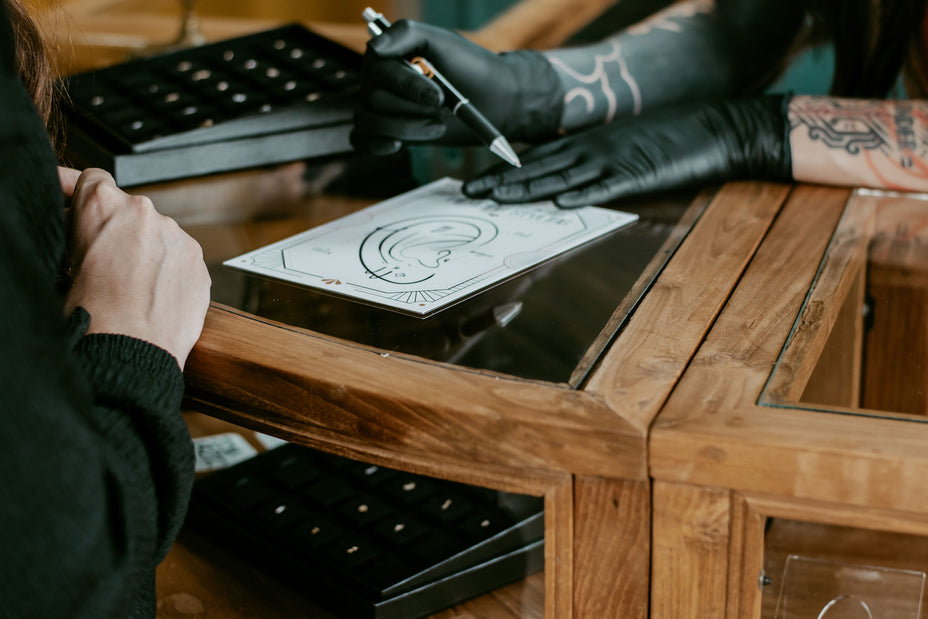 Afbeelding van iemand die een piercingstyling op papier uitwerkt, voorbereiding op ear styling