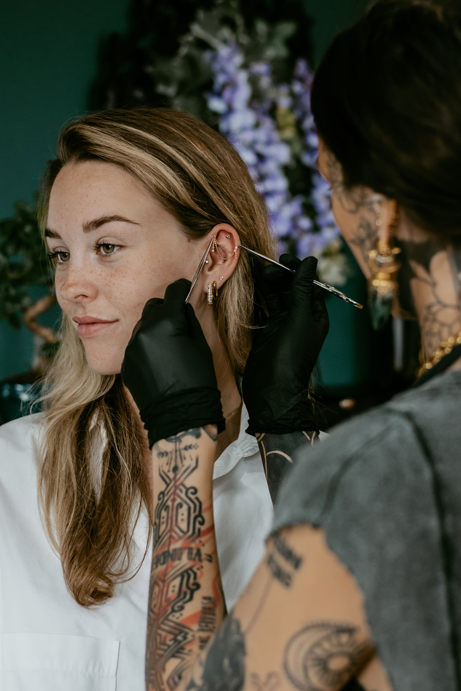Piercingsieraad wordt voor het oor gehouden tijdens een proefpassing als onderdeel van een styling bij All Perfectly Pierced