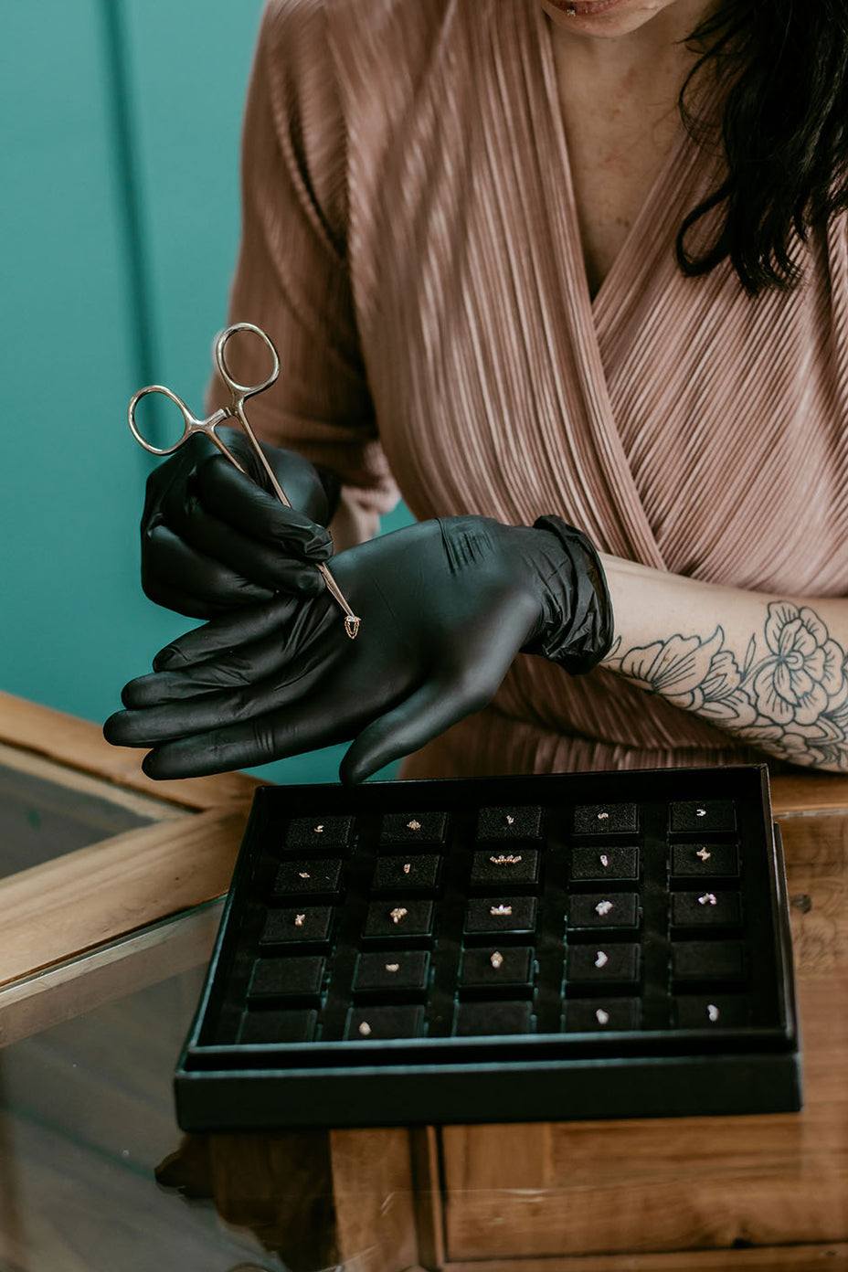 Hand van een medewerker die een luxe piercing sieraad toont bij All Perfectly Pierced, met aandacht voor detail en kwaliteit.